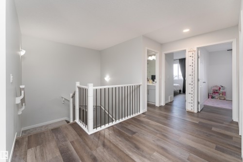 Upper-level landing featuring wood-finish flooring, white trim, recessed lighting, and a staircase with white newel posts and black metal spindles - 5323 Lark Landing Landing, Edmonton, AB - Indoor Photo Showing Other Room