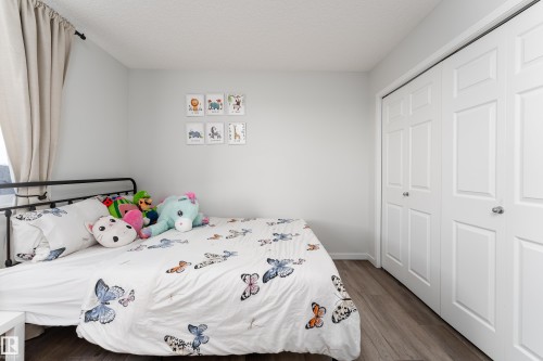 Bedroom featuring light gray walls, wood-finish flooring, and white bi-fold closet doors with chrome hardware - 5323 Lark Landing Landing, Edmonton, AB - Indoor Photo Showing Bedroom