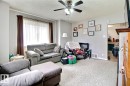 Carpeted living area featuring a ceiling fan with light fixture, window with drapes, and a doorway to an additional room - 11626 87 Street, Edmonton, AB  - Indoor Photo Showing Living Room 