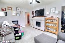 Interior living area featuring a central fireplace with light-toned tile surround and a patterned accent band - 11626 87 Street, Edmonton, AB  - Indoor Photo Showing Living Room With Fireplace 