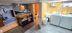 Laundry area featuring wood-finish flooring, wood paneling, and a utility sink - 