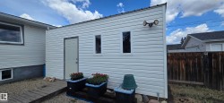 White vinyl-sided exterior structure with a metal roof and two windows - 