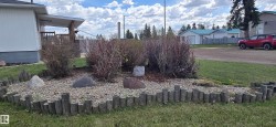 Landscaped garden bed featuring decorative rocks, mature shrubs, and a wood-log border - 