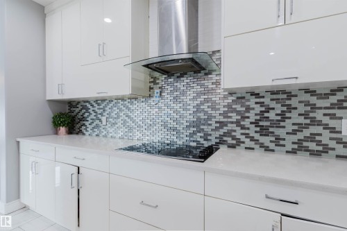 Sleek kitchen featuring white flat-panel cabinetry and a mosaic tile backsplash - 17030 62 Street, Edmonton, AB - Indoor Photo Showing Kitchen With Upgraded Kitchen
