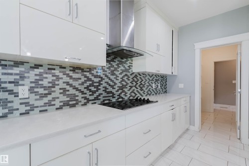 Contemporary kitchen featuring white cabinetry, a glass tile backsplash, and a built-in cooktop - 17030 62 Street, Edmonton, AB - Indoor Photo Showing Kitchen With Upgraded Kitchen