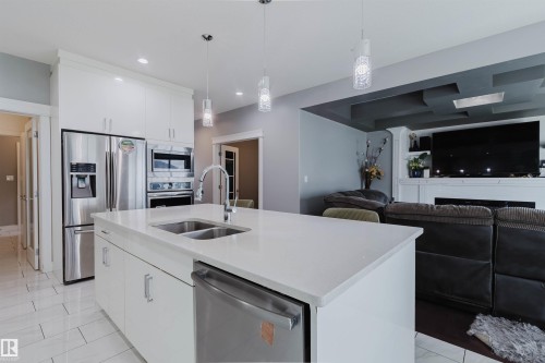 Modern kitchen featuring a large island with an undermount double sink and stainless steel appliances - 17030 62 Street, Edmonton, AB - Indoor Photo Showing Kitchen With Double Sink With Upgraded Kitchen