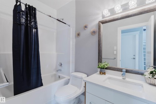 Bathroom featuring a full vanity with a white countertop and integrated sink, a large framed mirror, and an overhead vanity light fixture - 17030 62 Street, Edmonton, AB - Indoor Photo Showing Bathroom