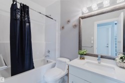 Bathroom featuring a full vanity with a white countertop and integrated sink, a large framed mirror, and an overhead vanity light fixture - 