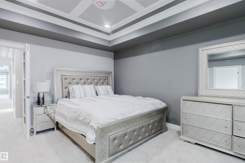 Bedroom with a tray ceiling featuring recessed lighting, light gray carpeting, and a contrasting dark gray accent wall - 17030 62 Street, Edmonton, AB - Indoor Photo Showing Bedroom