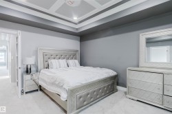 Bedroom with a tray ceiling featuring recessed lighting, light gray carpeting, and a contrasting dark gray accent wall - 