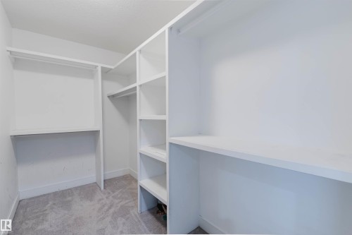 Walk-in closet featuring white built-in shelving, hanging rods, and light gray carpeting - 17030 62 Street, Edmonton, AB - Indoor With Storage