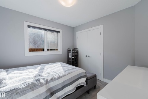 Bedroom featuring light gray walls, white trim, a double-panel closet door, and a single window with a roller shade - 17030 62 Street, Edmonton, AB - Indoor Photo Showing Bedroom