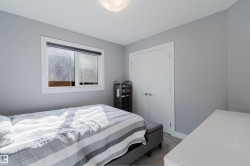 Bedroom featuring light gray walls, white trim, a double-panel closet door, and a single window with a roller shade - 