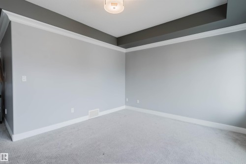 Spacious interior featuring a neutral color palette, tray ceiling with contrasting accent, white crown molding, white baseboards, and light gray carpet - 17030 62 Street, Edmonton, AB - Indoor Photo Showing Other Room