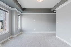 Spacious room featuring light gray wall paint, crisp white trim, and a tray ceiling with a darker accent color - 