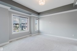 Spacious room featuring light gray walls, white trim, and a tray ceiling with a contrasting dark gray accent - 