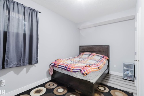 Bedroom featuring light gray walls, window with blinds, wood-finish flooring, and a white door with a lever handle - 17030 62 Street, Edmonton, AB - Indoor Photo Showing Bedroom