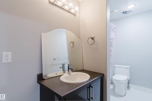 Bathroom vanity featuring an integrated sink, dark wood-finish cabinetry, and a countertop - 17030 62 Street, Edmonton, AB - Indoor Photo Showing Bathroom