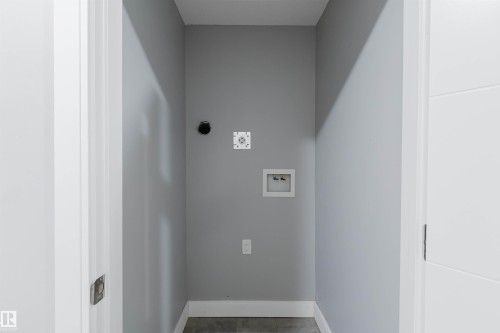 Dedicated laundry area featuring modern gray walls, white baseboards, and dark gray flooring - 17030 62 Street, Edmonton, AB - Indoor Photo Showing Other Room