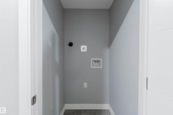 Dedicated laundry area featuring modern gray walls, white baseboards, and dark gray flooring - 