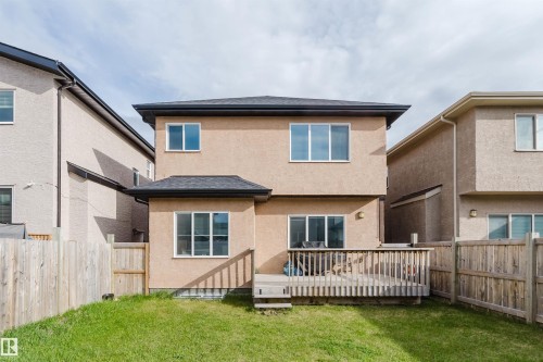 Rear exterior with a wood-fenced yard, stucco siding, a ground-level wood deck, and multiple windows - 17030 62 Street, Edmonton, AB - Outdoor With Deck Patio Veranda With Exterior