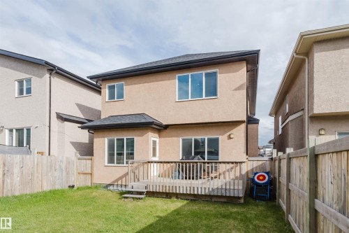 Rear exterior featuring a spacious wood deck, stucco siding, and a fenced yard with green lawn - 17030 62 Street, Edmonton, AB - Outdoor With Deck Patio Veranda With Exterior