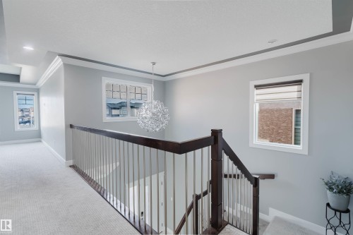 Upper-level landing featuring a contemporary chandelier, recessed lighting, white trim, dark wood-finish handrail, and light-tone carpeting - 17030 62 Street, Edmonton, AB - Indoor Photo Showing Other Room