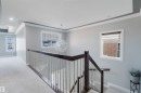 Upper-level landing featuring a contemporary chandelier, recessed lighting, white trim, dark wood-finish handrail, and light-tone carpeting - 17030 62 Street, Edmonton, AB  - Indoor Photo Showing Other Room 