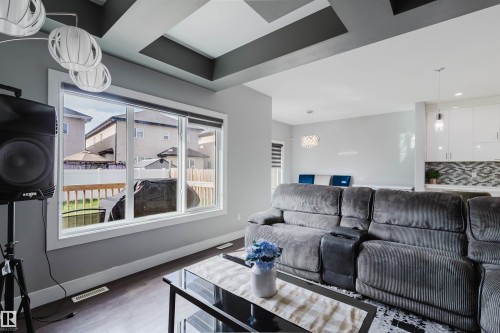 Living area with coffered ceiling featuring geometric accents, wood-finish flooring, and a large window overlooking a wooden deck - 17030 62 Street, Edmonton, AB - Indoor Photo Showing Living Room