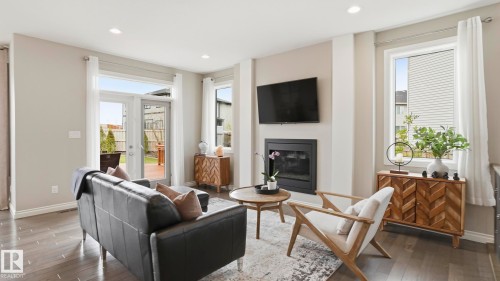 Living area featuring wood-finish flooring, a contemporary fireplace with a black surround, recessed lighting, and white trim - 2620 Adam Crest, Edmonton, AB - Indoor Photo Showing Living Room With Fireplace