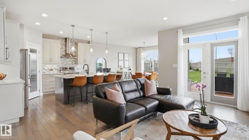 Open-concept living space featuring wood-finish flooring, recessed lighting, and a kitchen island with seating - 2620 Adam Crest, Edmonton, AB - Indoor