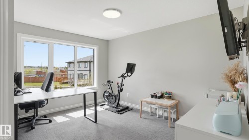 Spacious room with large windows, light gray walls, gray carpeting, and a flush-mount ceiling light fixture - 2620 Adam Crest, Edmonton, AB - Indoor Photo Showing Office