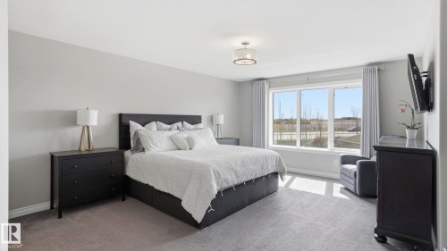 Carpeted bedroom featuring a large triple window, light gray walls, and a contemporary ceiling light fixture - 2620 Adam Crest, Edmonton, AB - Indoor Photo Showing Bedroom