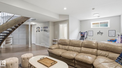 Finished lower level featuring wood-finish flooring, a contemporary open-riser staircase with metal balusters, and recessed ceiling lighting - 2620 Adam Crest, Edmonton, AB - Indoor Photo Showing Living Room