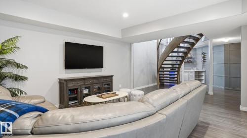 Lower level entertainment area featuring wood-finish flooring, a built-in wet bar, and a curved wooden staircase with metal balusters - 2620 Adam Crest, Edmonton, AB - Indoor