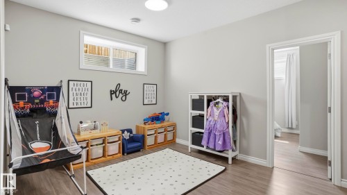 Bright interior room featuring a high window, wood-finish flooring, and light gray wall paint - 2620 Adam Crest, Edmonton, AB - Indoor