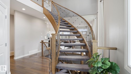 Curved staircase featuring carpeted treads, wood handrails, and wrought iron balusters - 2620 Adam Crest, Edmonton, AB - Indoor Photo Showing Other Room