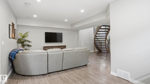 Open-concept lower level featuring wood-finish flooring, recessed lighting, and a modern spiral staircase - 2620 Adam Crest, Edmonton, AB - Indoor