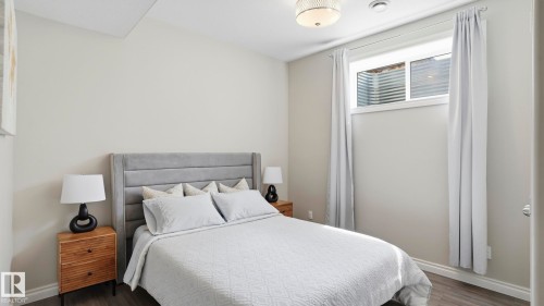 Bedroom featuring wood-finish flooring, a contemporary ceiling light fixture, neutral wall colors, white baseboards, and a window with white trim - 2620 Adam Crest, Edmonton, AB - Indoor Photo Showing Bedroom