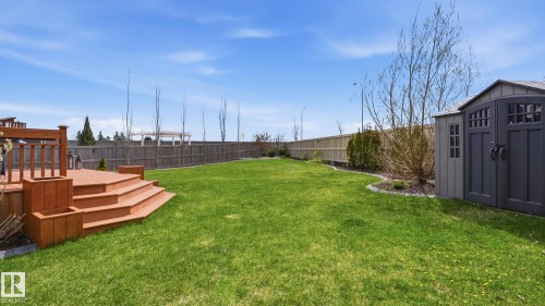 Expansive backyard featuring a tiered wood deck, substantial green lawn, perimeter fencing, a garden shed, and mature plantings - 2620 Adam Crest, Edmonton, AB - Outdoor