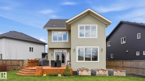 Rear exterior featuring a multi-level wood deck with steps, dual French doors, light-toned siding, and upper-level windows - 2620 Adam Crest, Edmonton, AB - Outdoor With Deck Patio Veranda