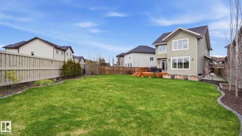 Expansive backyard featuring a manicured lawn, multi-level wood deck, privacy fencing, and raised garden beds - 2620 Adam Crest, Edmonton, AB - Outdoor