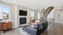 Open concept living space featuring a curved wood staircase with wrought iron spindles, a sleek black fireplace surround, and recessed lighting - 2620 Adam Crest, Edmonton, AB  - Indoor Photo Showing Living Room With Fireplace 