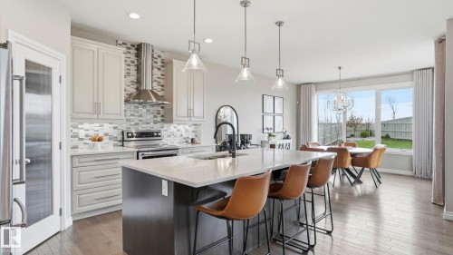 Open-concept kitchen featuring light-toned cabinetry, a spacious island with a light-colored countertop, and stainless steel appliances - 2620 Adam Crest, Edmonton, AB - Indoor Photo Showing Kitchen With Upgraded Kitchen