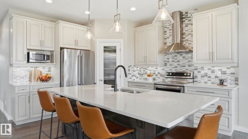 Kitchen island with white countertop, undermount sink, and black faucet - 2620 Adam Crest, Edmonton, AB - Indoor Photo Showing Kitchen With Stainless Steel Kitchen With Double Sink With Upgraded Kitchen