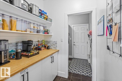 Pantry area featuring wood-finish countertops, white cabinetry, open shelving, and a tiled backsplash - 219 Cranberry Bend, Fort Saskatchewan, AB - Indoor Photo Showing Other Room