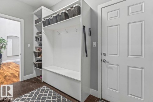 Mudroom featuring built-in white shelving, integrated bench seating, coat hooks, and a paneled entry door - 219 Cranberry Bend, Fort Saskatchewan, AB - Indoor Photo Showing Other Room