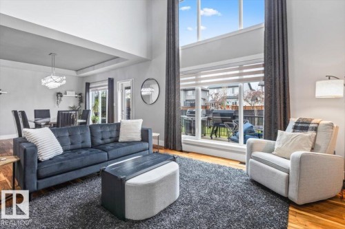 Two-story living area featuring extensive window treatments, hardwood flooring, and a tray ceiling - 219 Cranberry Bend, Fort Saskatchewan, AB - Indoor Photo Showing Living Room