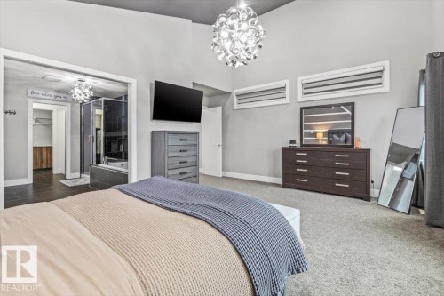 Spacious room featuring vaulted ceilings, a contemporary ceiling light fixture, two horizontal transom windows, and light gray wall paint - 219 Cranberry Bend, Fort Saskatchewan, AB - Indoor Photo Showing Bedroom