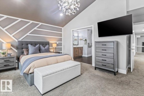 Carpeted bedroom featuring a vaulted ceiling and an accent wall with geometric paneling - 219 Cranberry Bend, Fort Saskatchewan, AB - Indoor Photo Showing Bedroom
